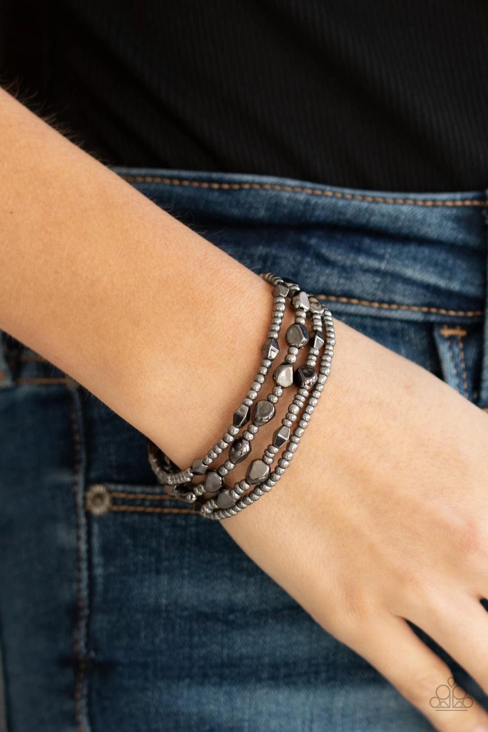 Paparazzi Accessories Fashionably Faceted - Black A shimmery collection of dainty gunmetal seed beads and faceted gunmetal accents are threaded along stretchy bands around the wrist, creating glistening layers. Jewelry