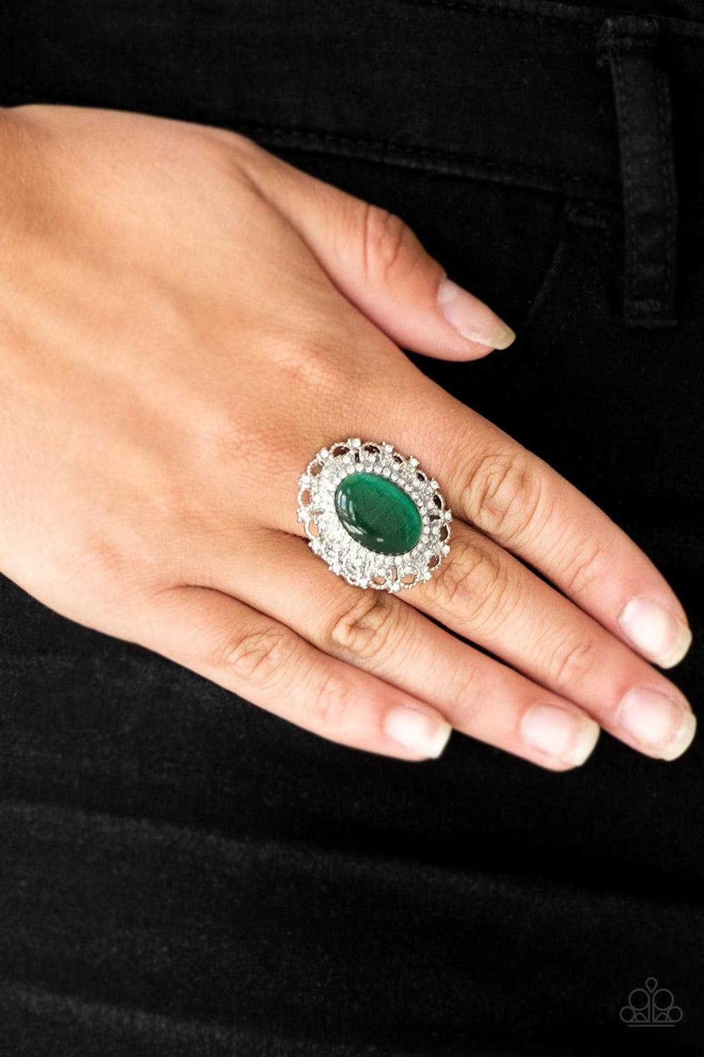 Paparazzi Accessories BAROQUE The Spell - Green Encrusted in dainty white rhinestones, a frilly silver frame spins around a glowing green moonstone center for a regal look. Features a stretchy band for a flexible fit Jewelry