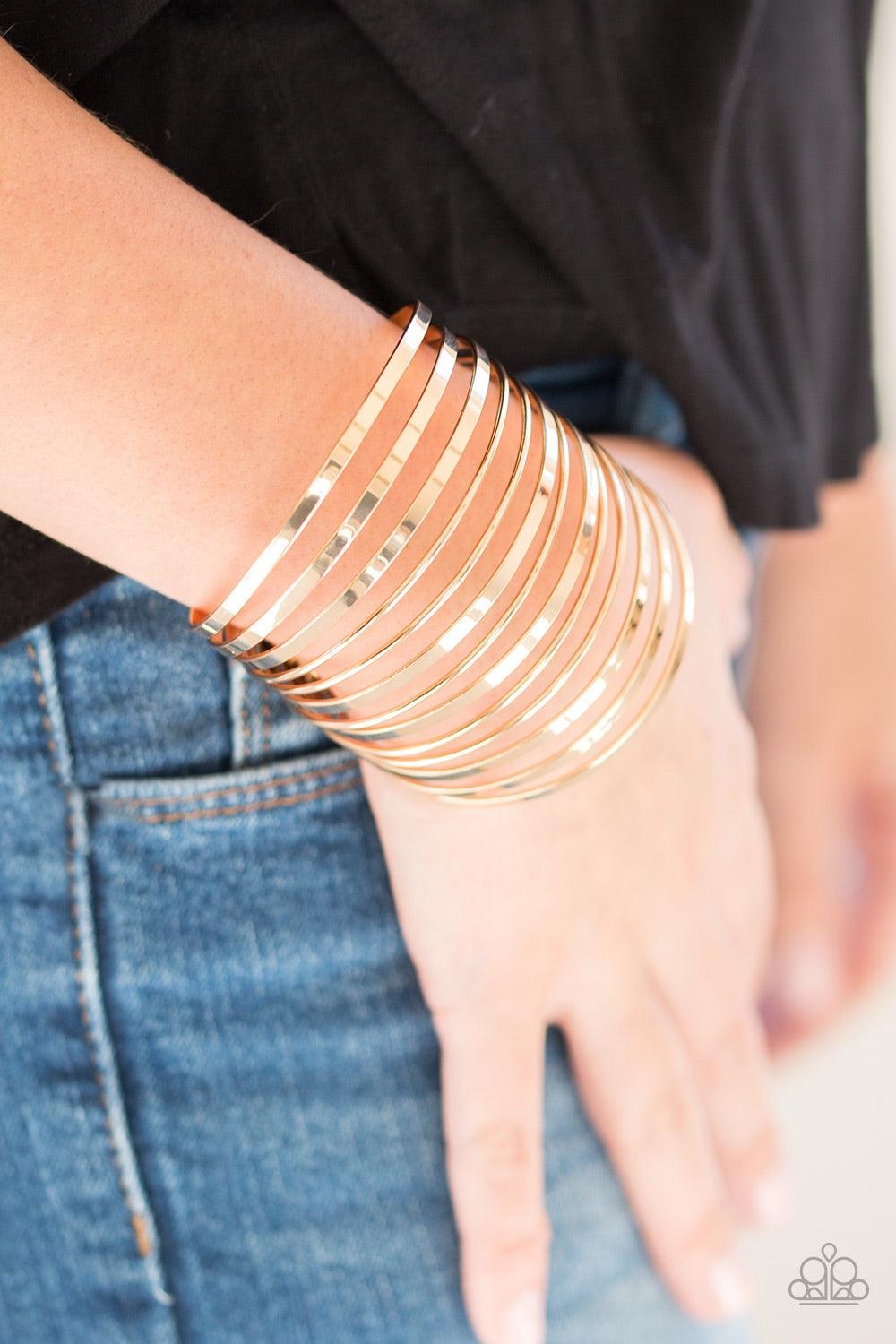 Paparazzi Accessories Front Line Shine - Gold Flat gold and dainty gold bars arc across the wrist, coalescing into a stacked cuff for a bold look. Jewelry