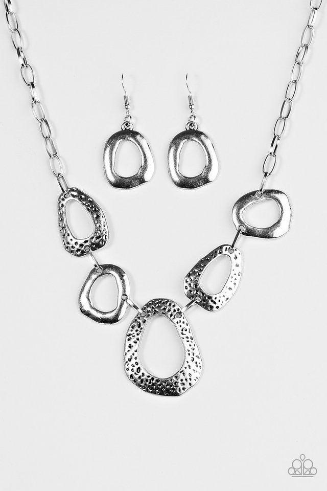 Paparazzi Accessories Very CAVE-alier ~Silver Delicately hammered and dotted with antiqued shimmer, asymmetrical silver frames link below the collar in a handcrafted, artisanal style. Features an adjustable clasp closure. Sold as one individual necklace.