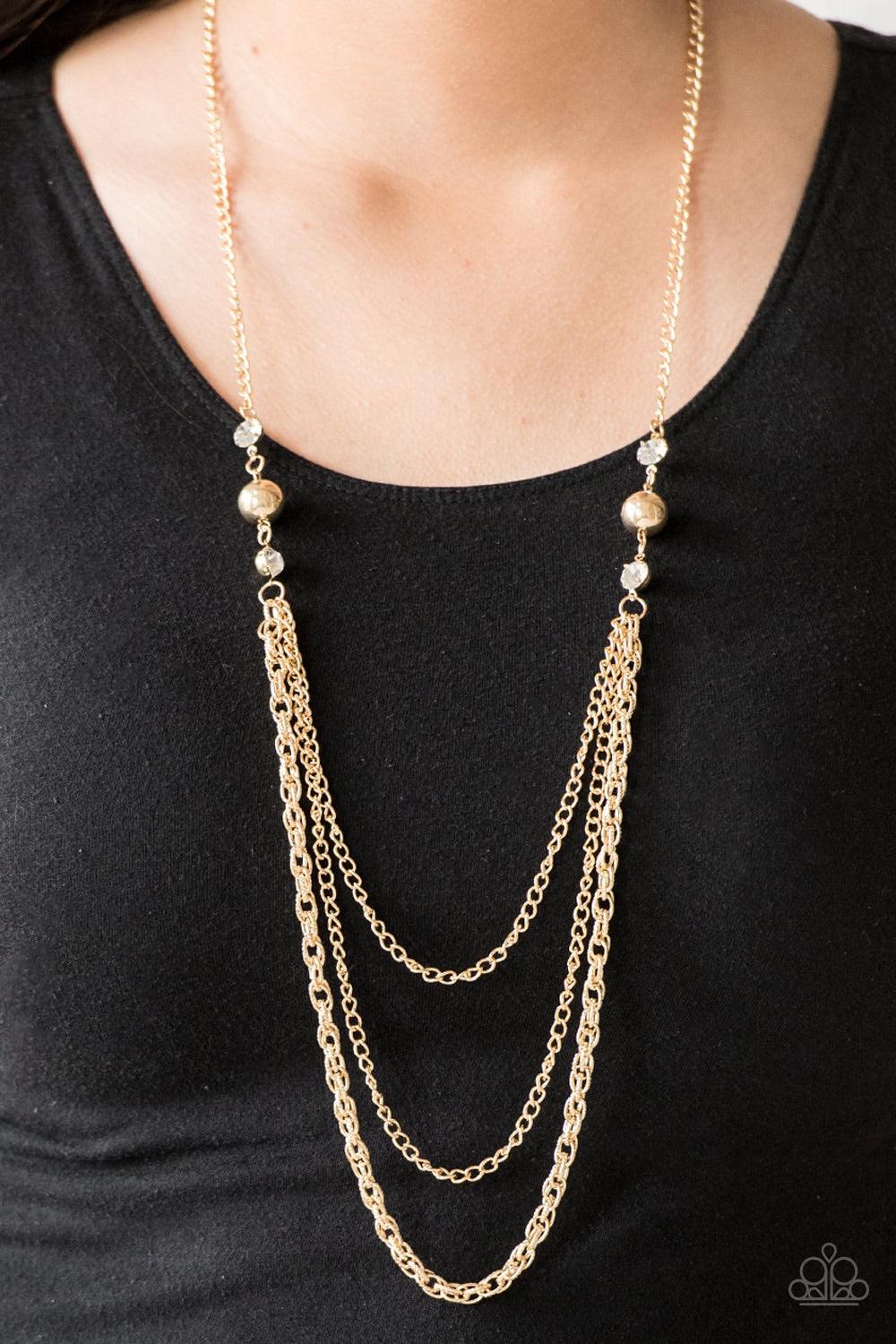 Paparazzi Accessories RITZ It All - Gold Glittery white rhinestones and oversized gold beads give way to layers of mismatched gold chains for a refined look. Features an adjustable clasp closure. Jewelry