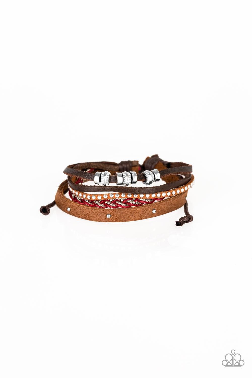 Paparazzi Accessories Day-Trip Trotter - Red Featuring an array of silver accents, mismatched brown leather and suede bands layer across the wrist. Red cording and dainty silver ball chain braid together, adding a refreshing splash of color to the seasona