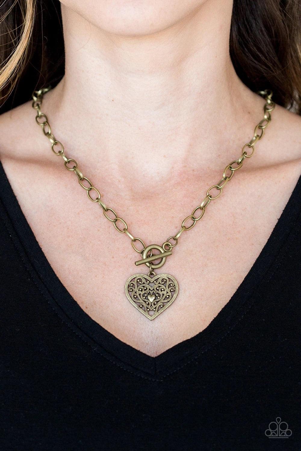 Paparazzi Accessories Victorian Romance ~Brass Brushed in an antiqued finish, brass filigree climbs a heart-shaped frame, creating a vintage inspired pendant below the collar. Features a toggle closure. Sold as one individual necklace. Includes one pair o
