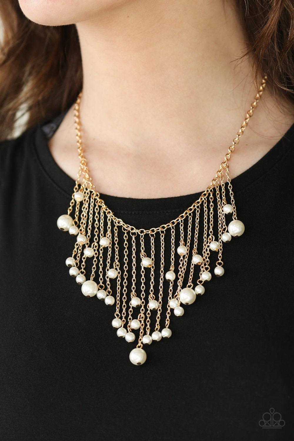 Paparazzi Accessories Catwalk Champ - Gold Varying in length, glistening gold chains swing from the bottom of a bold gold chain. Pearly white beads trickle down the chains, creating a fierce fringe below the collar. Features an adjustable clasp closure. S