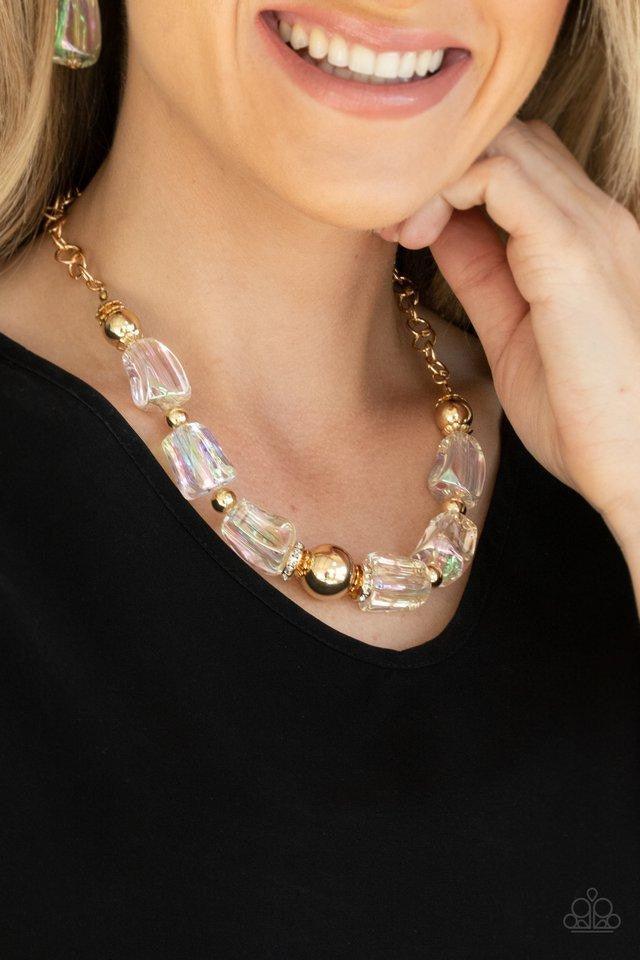 Paparazzi Accessories Iridescently Ice Queen - Gold Featuring an icy iridescence, glassy asymmetrical beads joins a mismatched collection of gold beads, white rhinestone encrusted rings, and scalloped gold accents below the collar. Attached to a gold chai