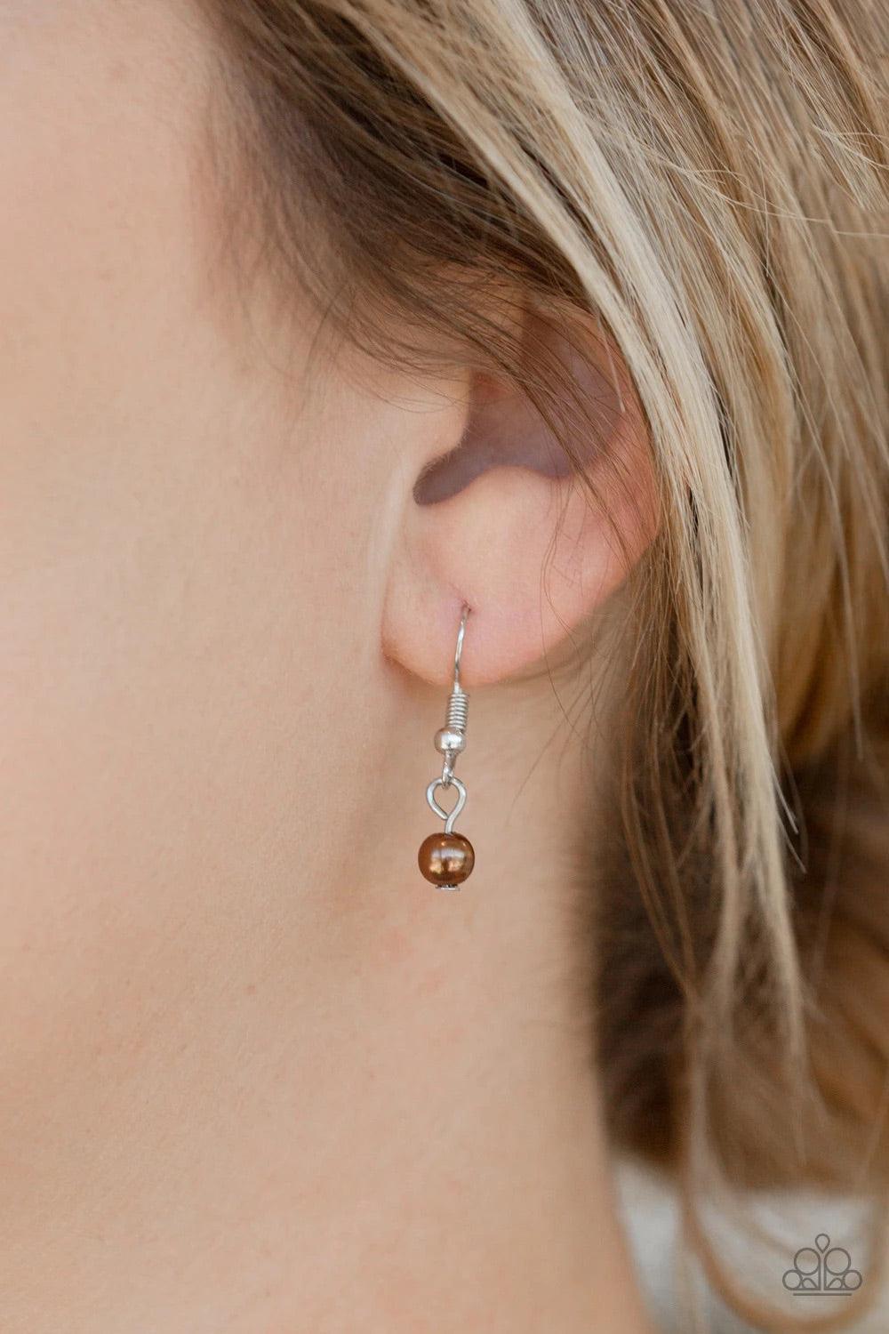 Paparazzi Accessories Be Fancy - Brown A solitaire brown pearl swings from the uppermost chain, giving way to a teardrop pendant and shimmery silver chain tassel. Dainty white rhinestones and brown pearls collect at the bottom of the centermost pendant fo