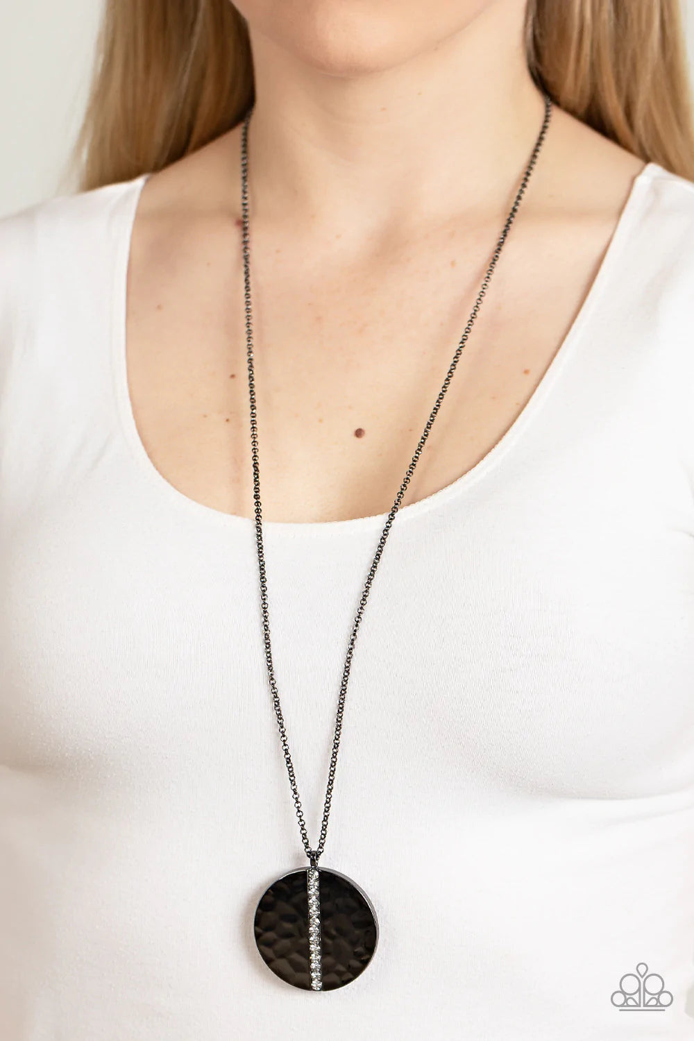 Paparazzi Accessories Token of My Gratitude - Black An icy row of glittering white rhinestones is pressed into the center of a hammered gunmetal disc, splitting the oversized pendant seemingly in two as it swings from the bottom of an extended gunmetal ch