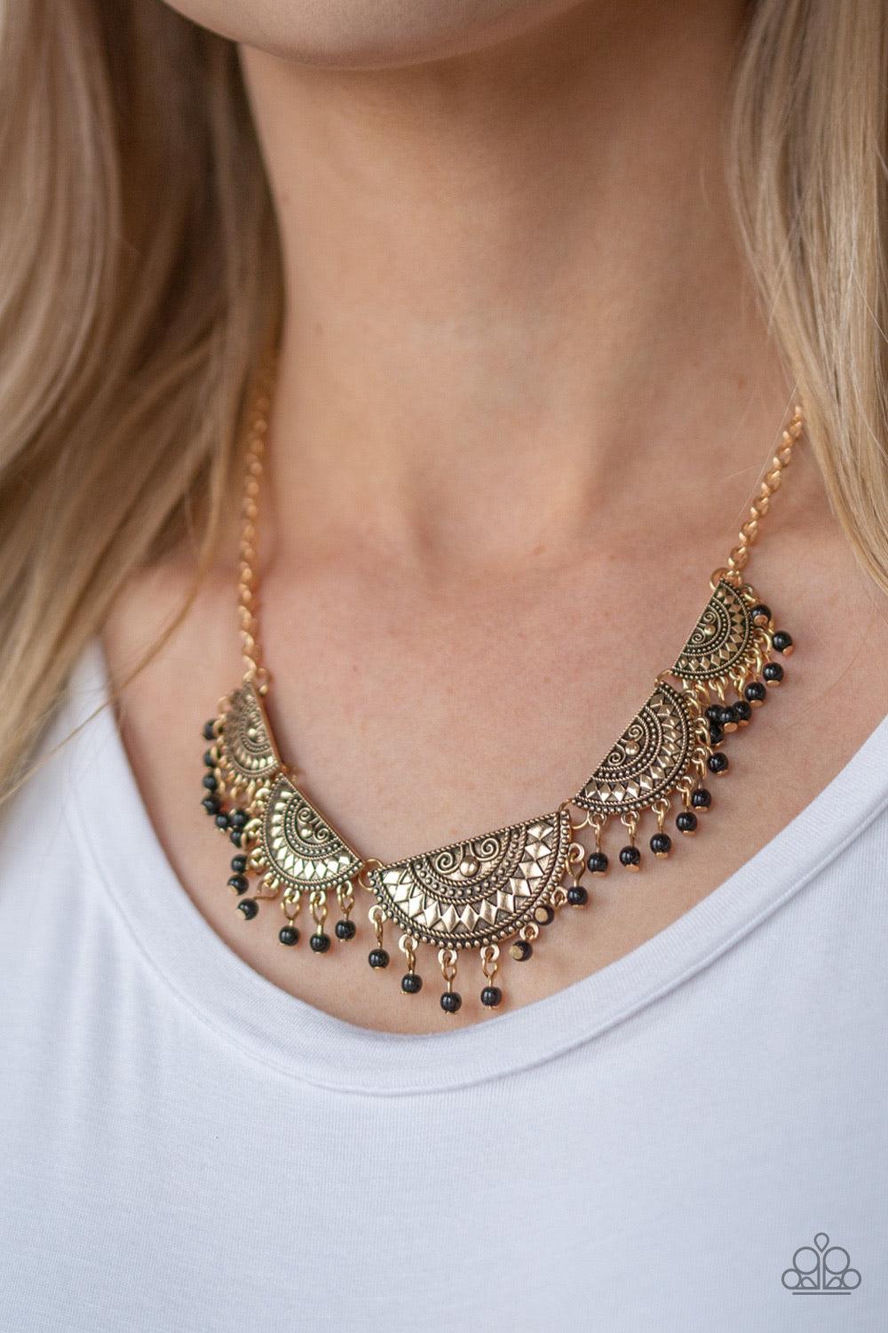 Paparazzi Accessories Boho Baby - Gold Embossed in tribal inspired patterns, gold half-moon frames link below the collar. Dainty black beads swing from the bottoms of the ornate frames, creating a flirtatious fringe. Features an adjustable clasp closure.
