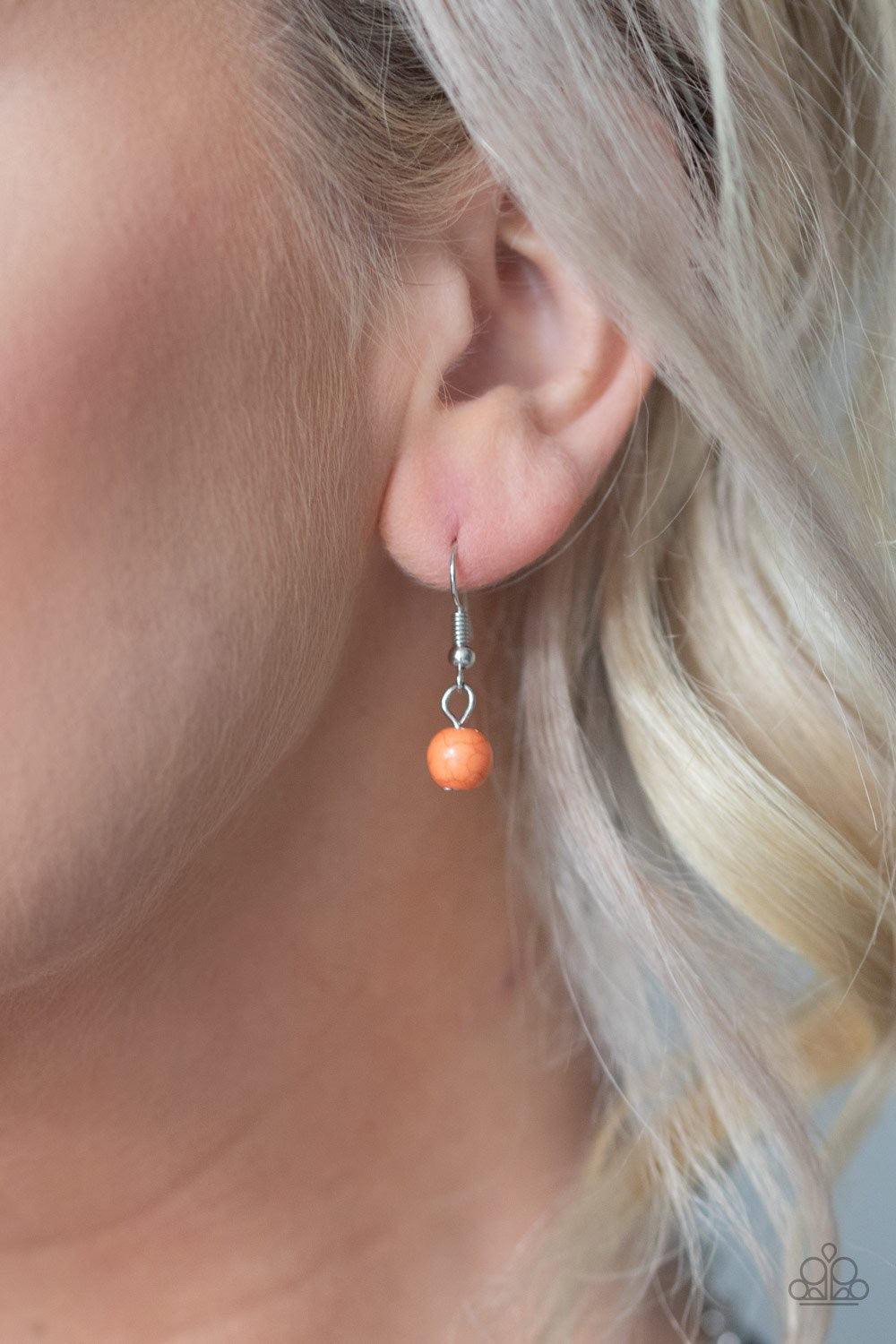 Paparazzi Accessories Desert Tranquility - Orange An earthy collection of dainty silver accents, rounded orange stone beads, and spotted ceramic-like beads are threaded along an invisible wire below the collar. An earthy wooden bead adorns the center, add