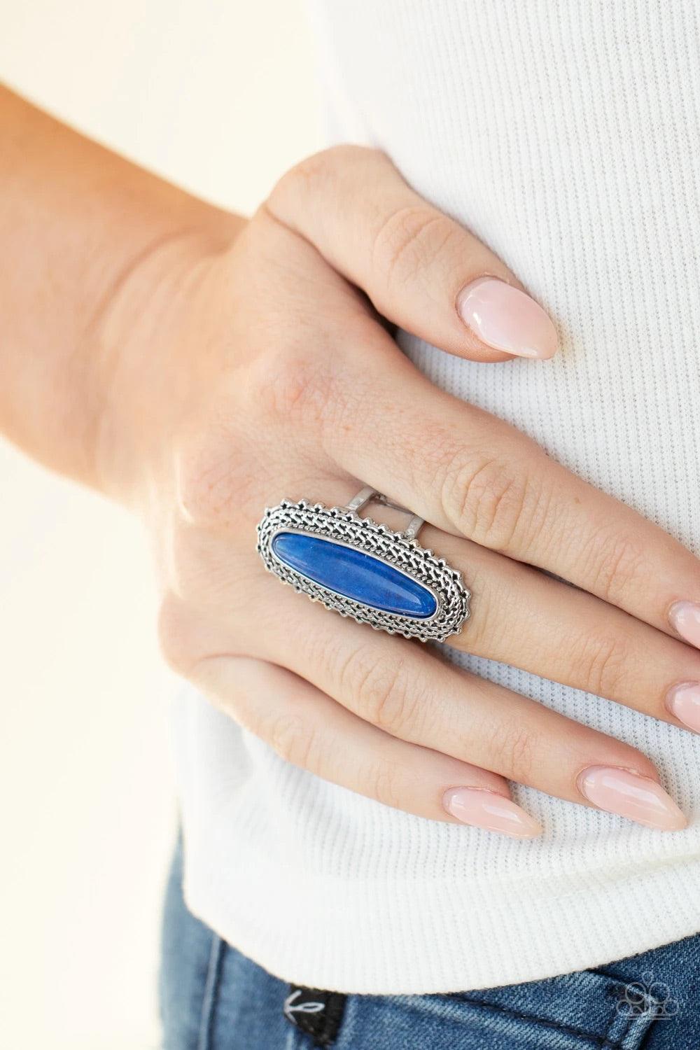 Paparazzi Accessories Mystical Mecca - Blue An oblong blue stone adorns the center of an elongated silver frame featuring mismatched silver textures for a bold artisan look. Features a stretchy band for a flexible fit. Sold as one individual ring. Jewelry