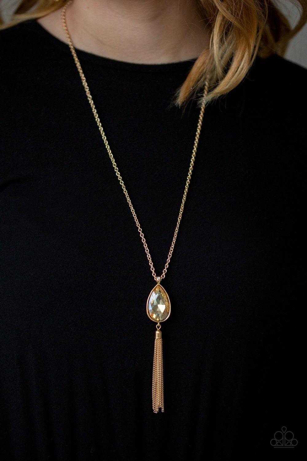 Paparazzi Accessories Elite Shine - Gold A golden teardrop gem swings from the bottom of a lengthened gold chain for a dramatic look. A shimmery gold chain tassel swings from the bottom of the pendant for a glamorous finish. Features an adjustable clasp c