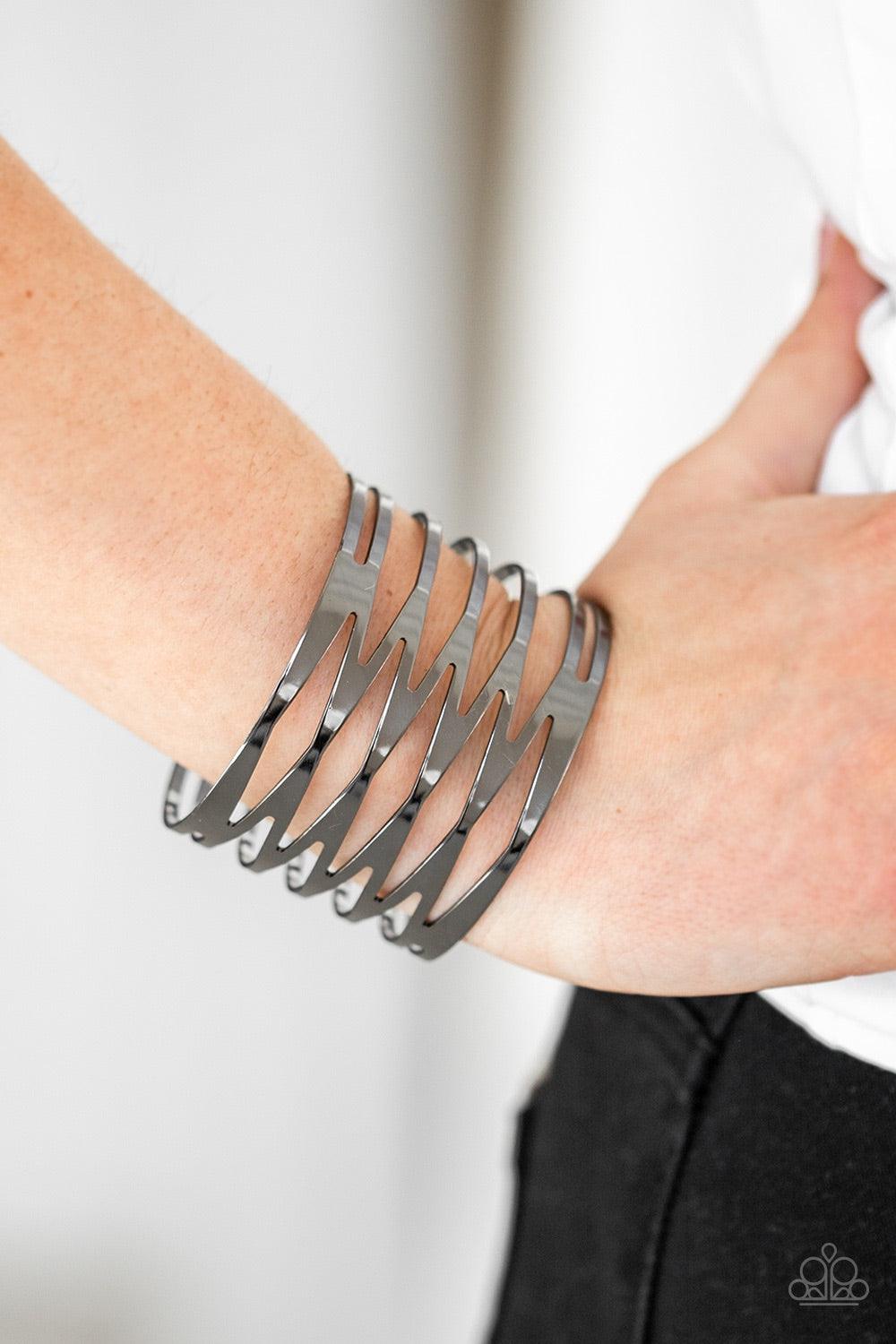 Paparazzi Accessories Keep Them On Edge - Black Brushed in a high-sheen finish, flat gunmetal bars race back and forth across the wrist, coalescing into an edgy cuff. Jewelry