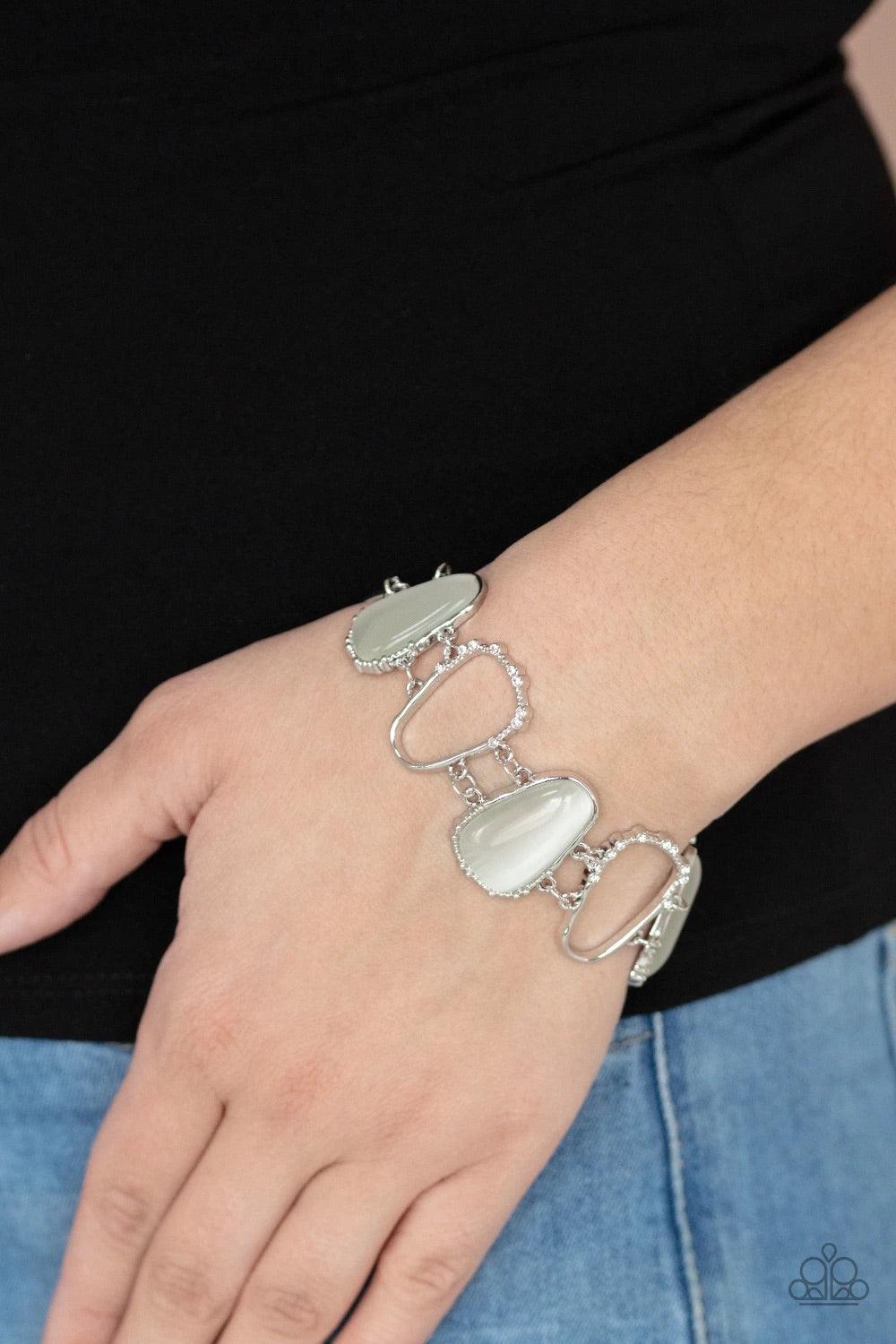 Paparazzi Accessories Yacht Club Couture - White Encased in studded silver frames, a tranquil collection of asymmetrical white cat’s eye stone teardrops and airy silver frames delicately link around the wrist for an ethereally sparkly display. A sprinklin