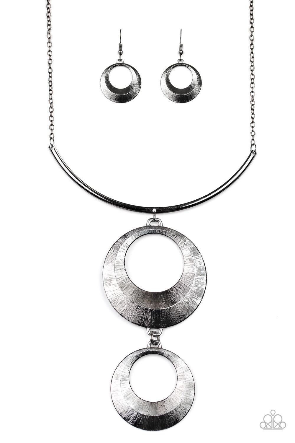 Paparazzi Accessories Egyptian Eclipse - Black Featuring a blinding scratch finish, two beveled gunmetal circular frames swing from the bottom of a bowing gunmetal rod, creating an edgy stacked pendant down the chest. Features an adjustable clasp closure.