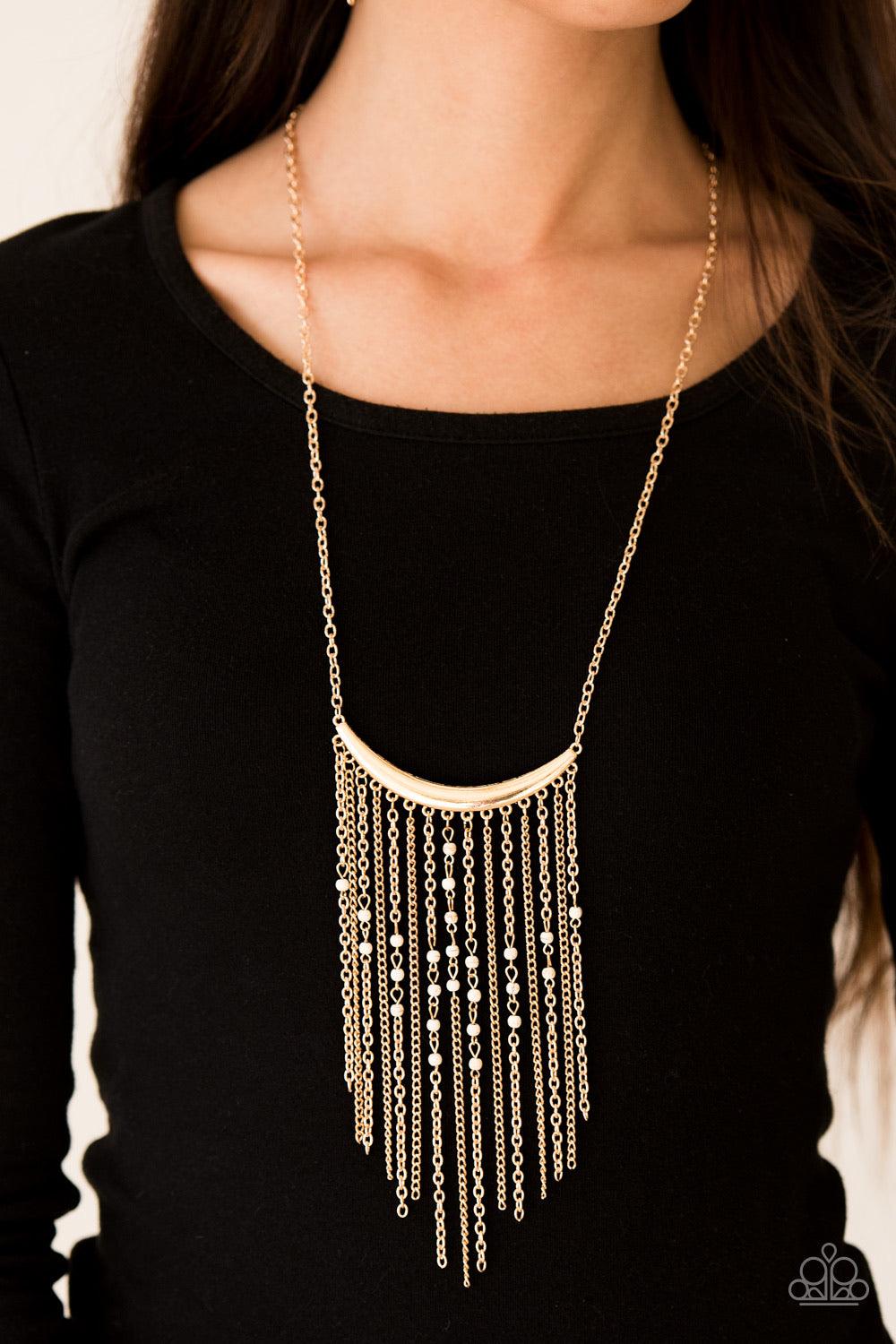 Paparazzi Accessories Runaway Rumba - Gold Glistening gold chains stream from the bottom of a shiny gold crescent, creating a bold tapered fringe down the chest. Dainty white stone beads sporadically trickle down the chains for a seasonal finish. Features