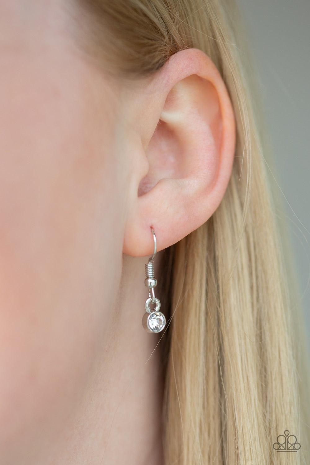 Paparazzi Accessories A Mother’s Love - Silver Swinging from the bottom of a lengthened silver chain, an asymmetrical heart pendant is stamped in the word, "mom" and dotted with a single white rhinestone for a whimsical look. Features an adjustable clasp