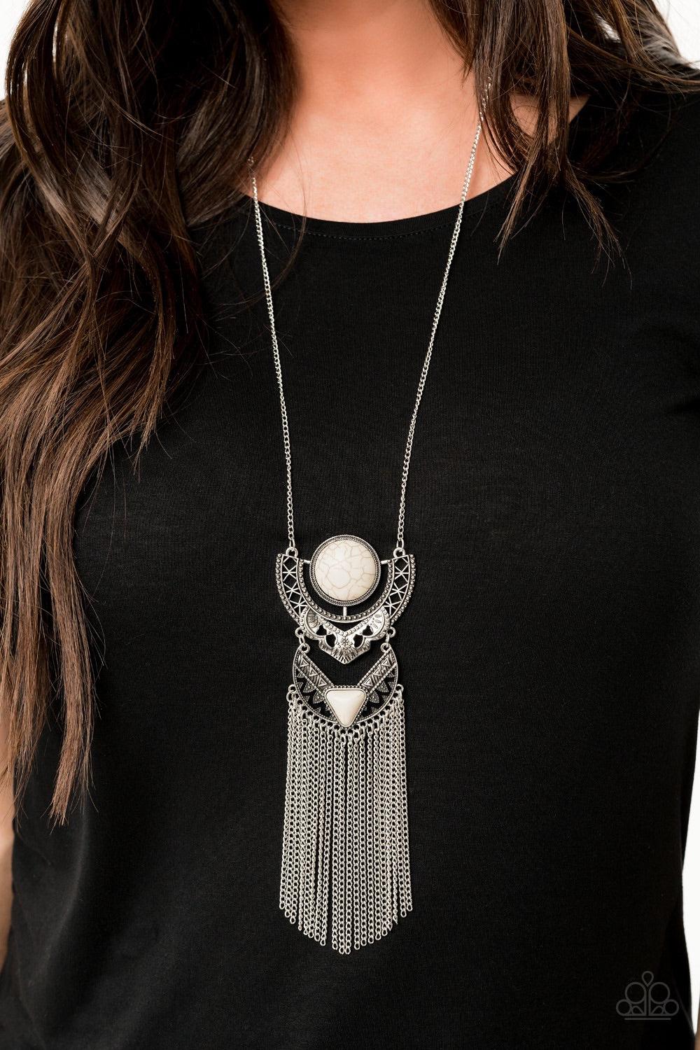 Paparazzi Accessories Spirit Trek - White Featuring refreshing white stone accents, ornate silver plates link at the bottom of a lengthened silver chain for a dramatic tribal look. Shimmery silver chains stream from the bottom of the stacked pendant, addi