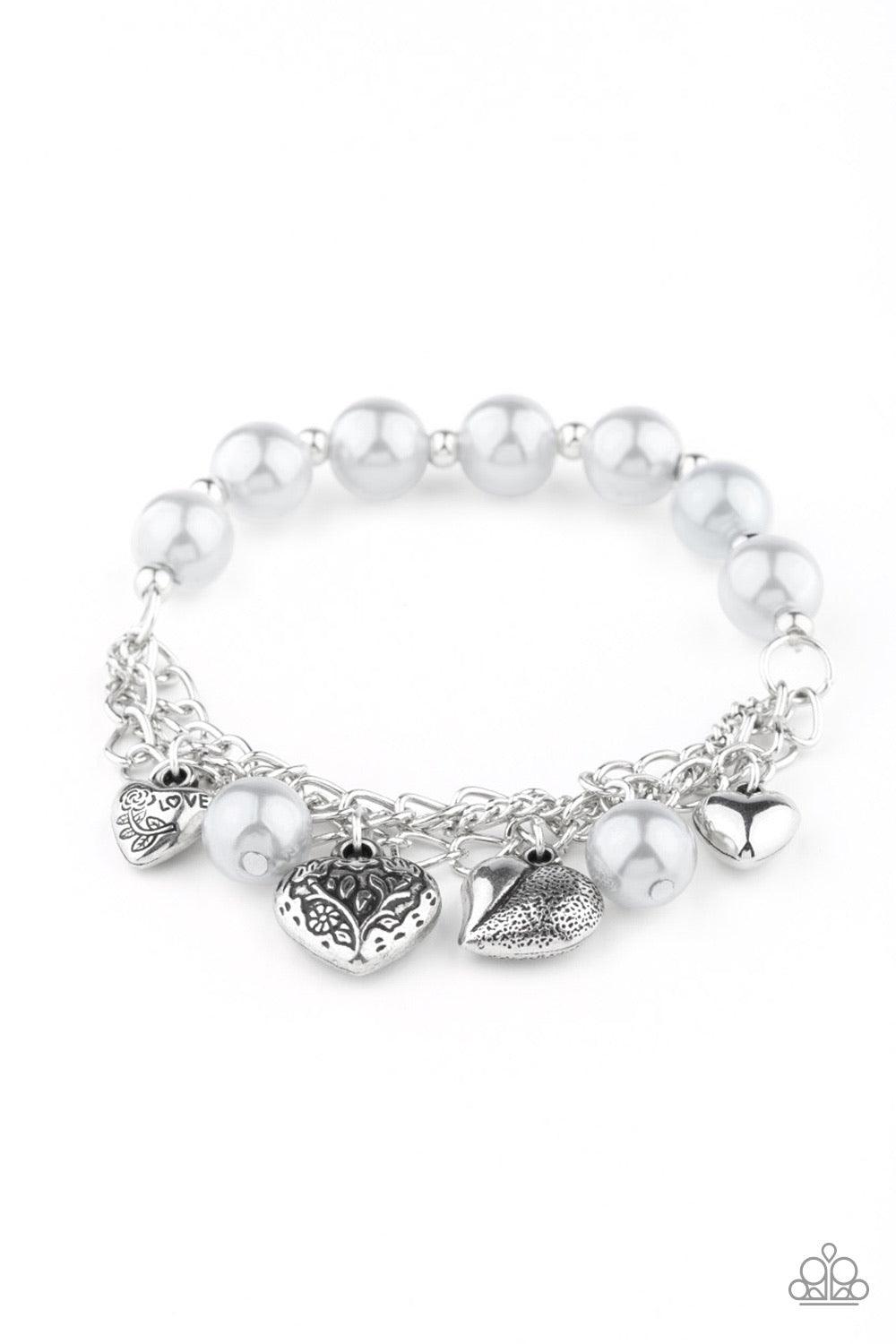 Paparazzi Accessories More Amour - Silver Attached to a section of shimmery silver chain, pearly gray and dainty silver beads are threaded along a stretchy band. Mismatched silver heart charms swing from the glistening chain, creating a flirty fringe. Sol