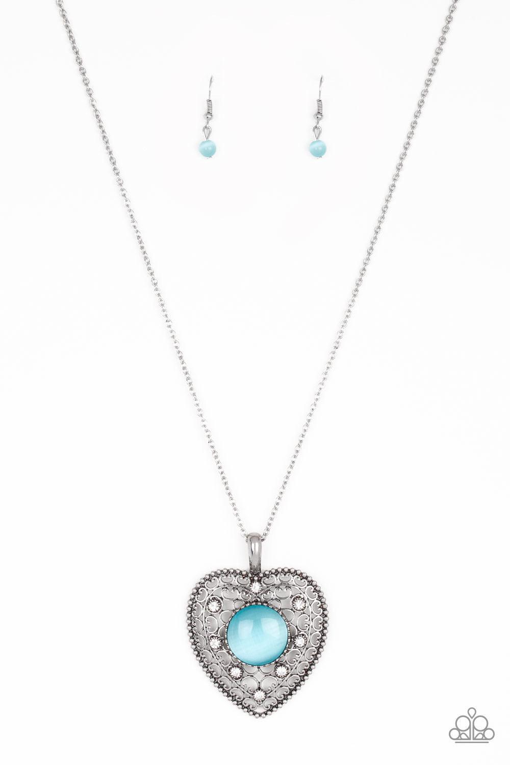 Paparazzi Accessories One Heart - Blue Featuring a glowing blue moonstone center, an oversized heart frame radiating with silver filigree and glittery white rhinestones swings from the bottom of a lengthened silver chain for a whimsical look. Features an