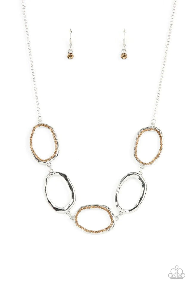 Paparazzi Accessories Gritty Go-Getter A row of dazzling light topaz rhinestones makes its way around a delicately hammered imperfect circular frame. The airy frames alternately link end to end with similar shiny silver frames creating a glitzy fashion ac