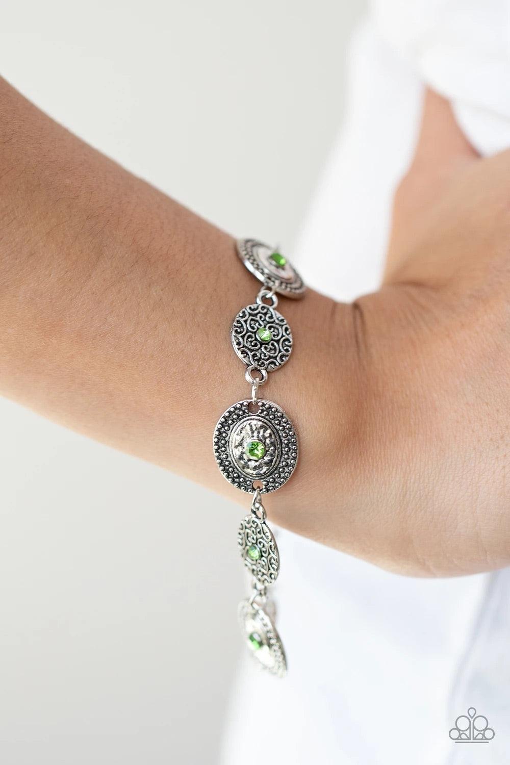 Paparazzi Accessories Secret Garden Glamour - Green Delicate Peridot rhinestones dot the centers of engraved antiqued silver discs. The dotted textures and heart shaped vines create a charming impression as they gracefully link around the wrist. Features