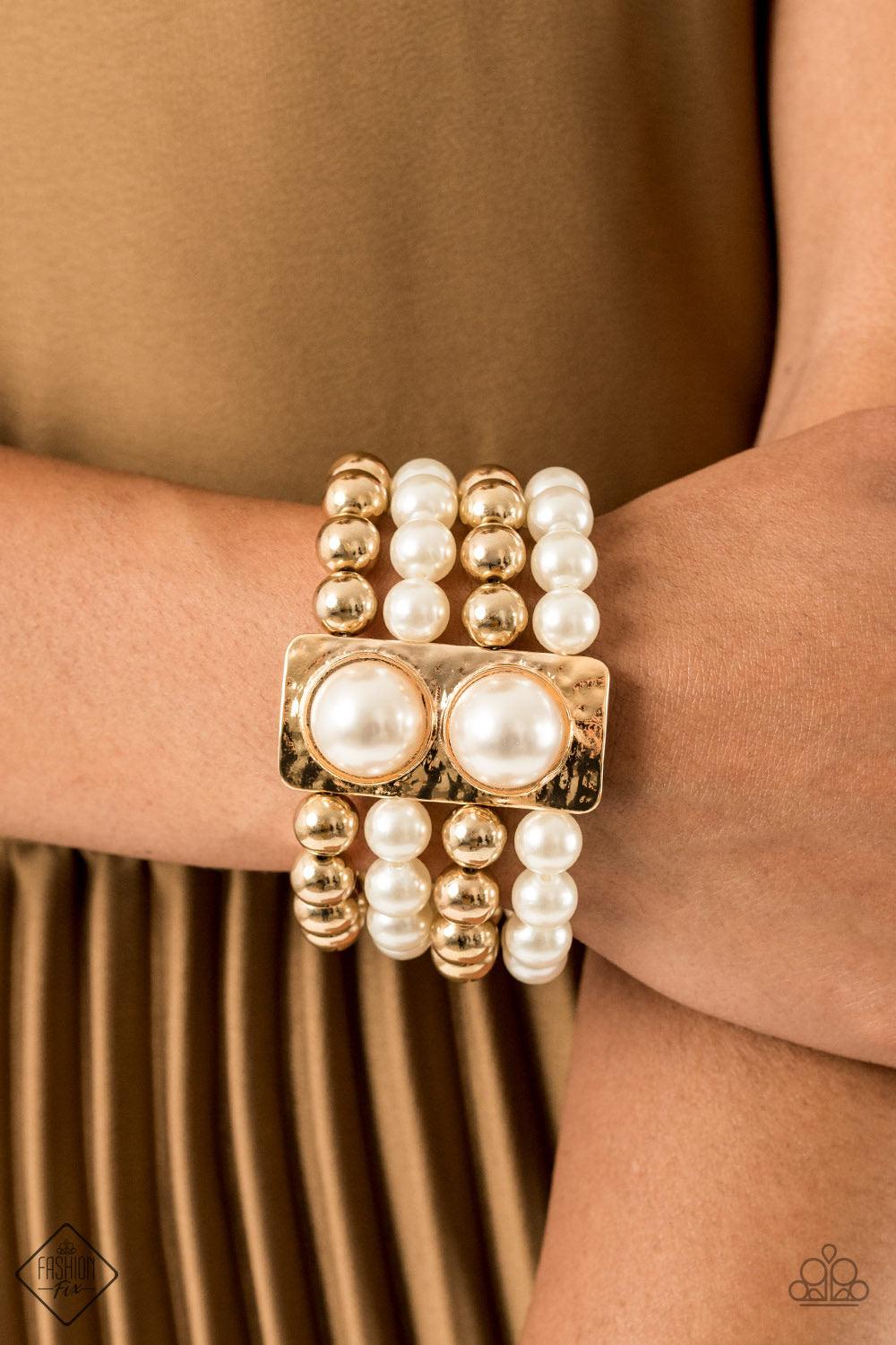 Paparazzi Accessories WEALTH-Conscious - Gold Held in place with a hammered gold frame dotted with two oversized white pearls, strands of classic gold beads and white pearls are threaded along stretchy bands that wrap around the wrist in a glamorously lay