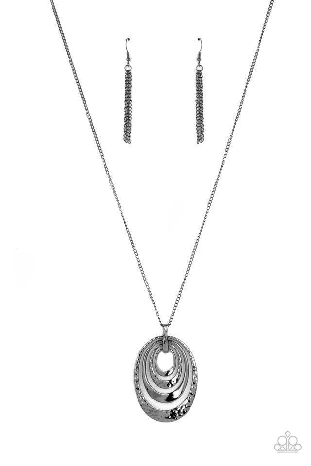 Paparazzi Accessories Renegade Ripples ~Black An asymmetrical collection of plain and hammered gunmetal ovals alternate at the bottom of a lengthened gunmetal chain, creating a dramatically stacked pendant. Features an adjustable clasp closure. Earrings