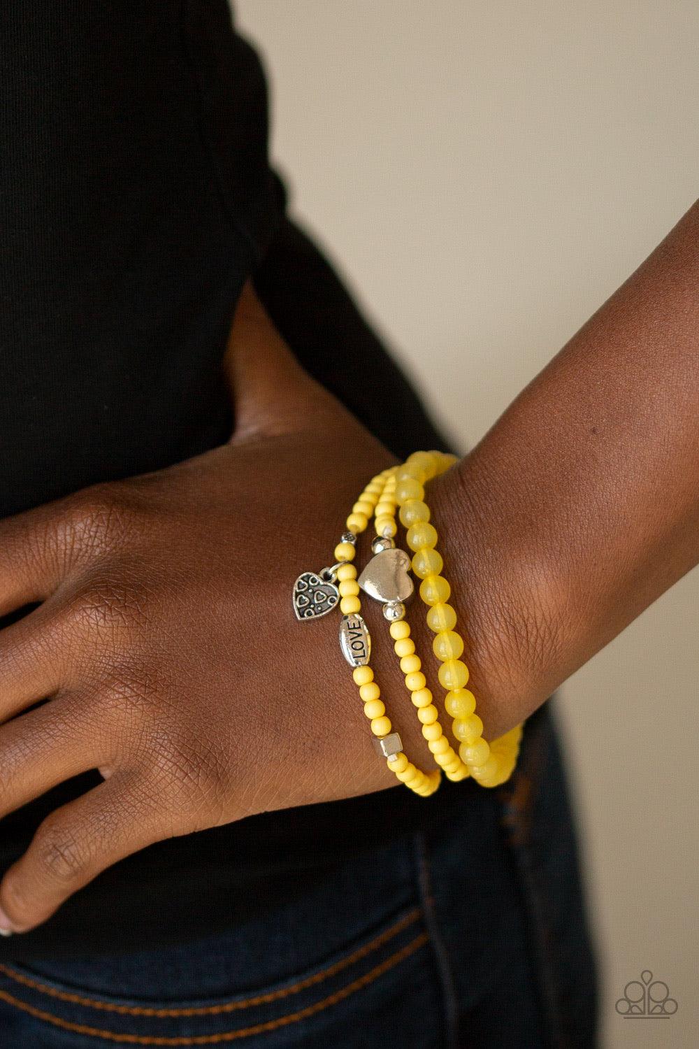 Paparazzi Accessories Really Romantic - Yellow An array of glassy and polished yellow beads are threaded along stretchy bands. Infused with silver accents, a collection of silver heart charms and a bead spelling out the word, "love", adorn the beaded stra