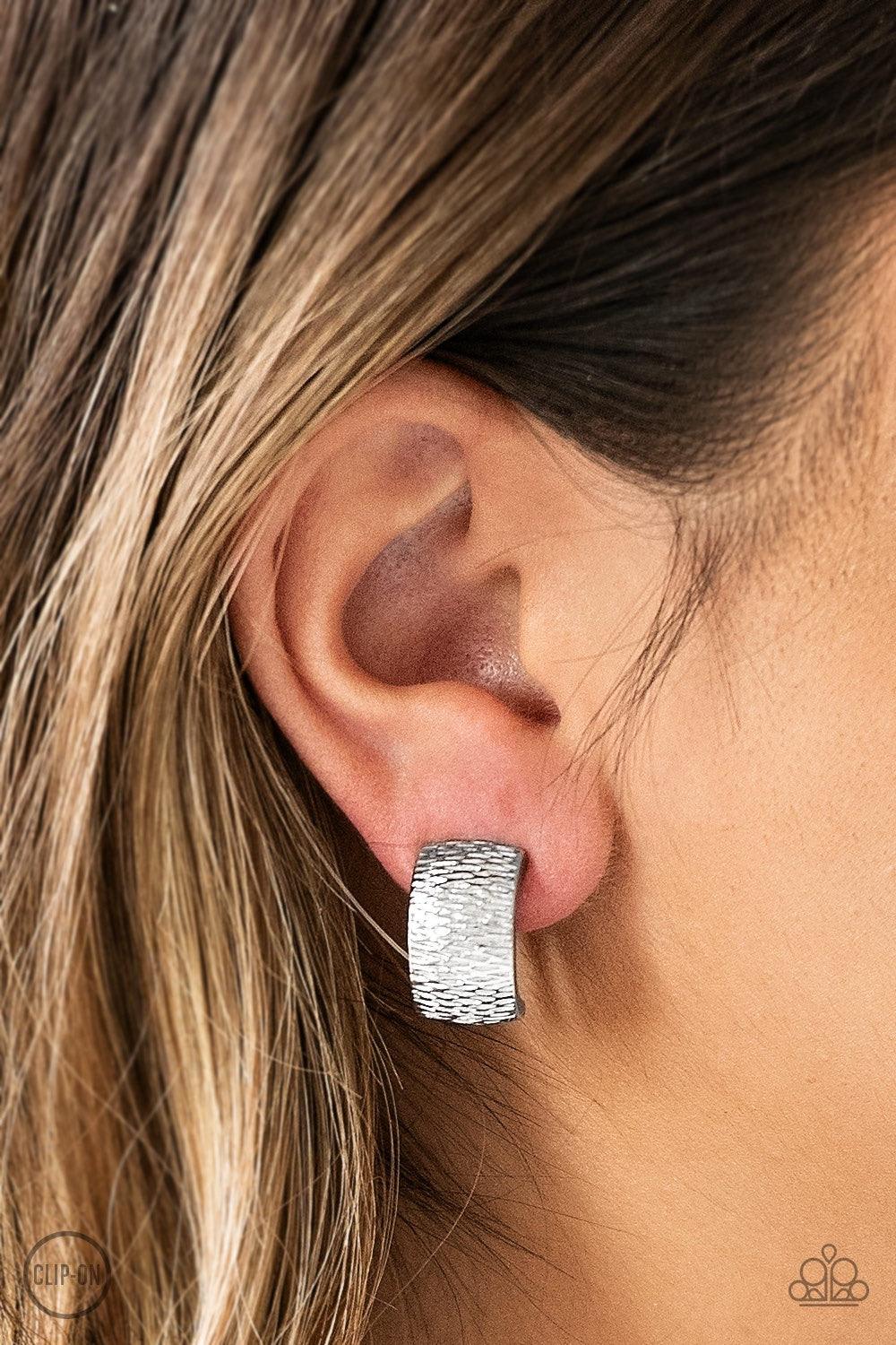 Paparazzi Accessories Cirque Du Couture - Silver *Clip-On Rippling with tactile textures, a shimmery silver ribbon curls into an edgy frame for a causal look. Earring attaches to a standard clip-on fitting. Jewelry