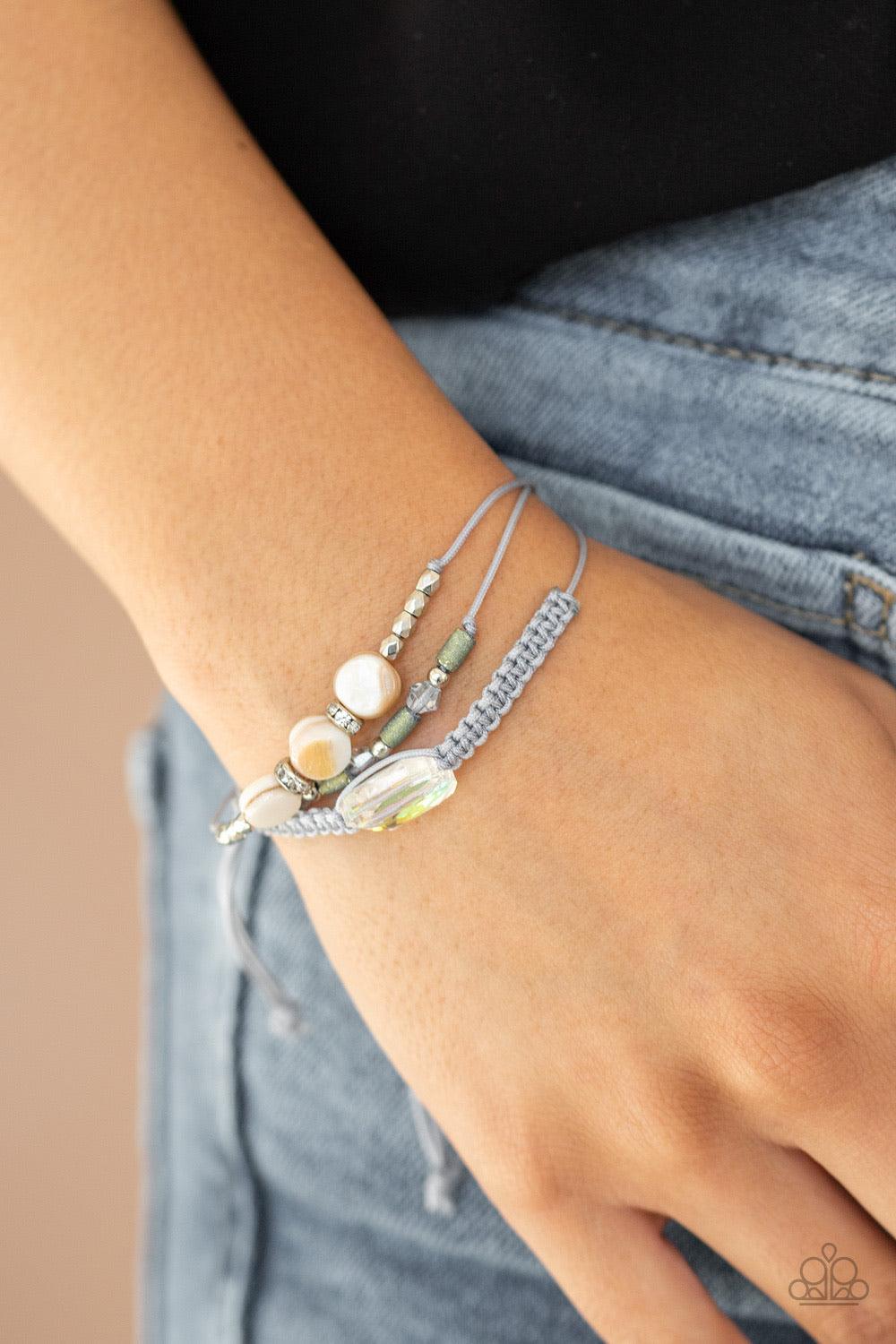 Paparazzi Accessories Prismatic Pathfinder - Multi A collection of shell-like beading, white rhinestone encrusted rings, metallic accents, and an opalescent gem are knotted in place across the wrist for a colorful flair. Features an adjustable sliding kno