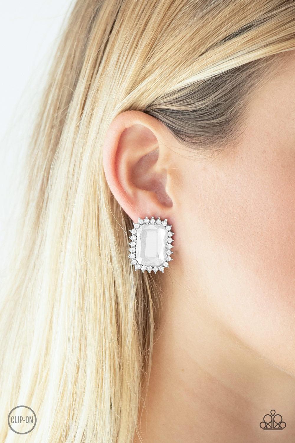 Paparazzi Accessories Insta Famous - White *Clip-On Featuring a regal emerald style cut, a dramatic white gem is pressed into the center of a silver frame radiating with glassy white rhinestones for a show-stopping look. Earring attaches to a standard cli