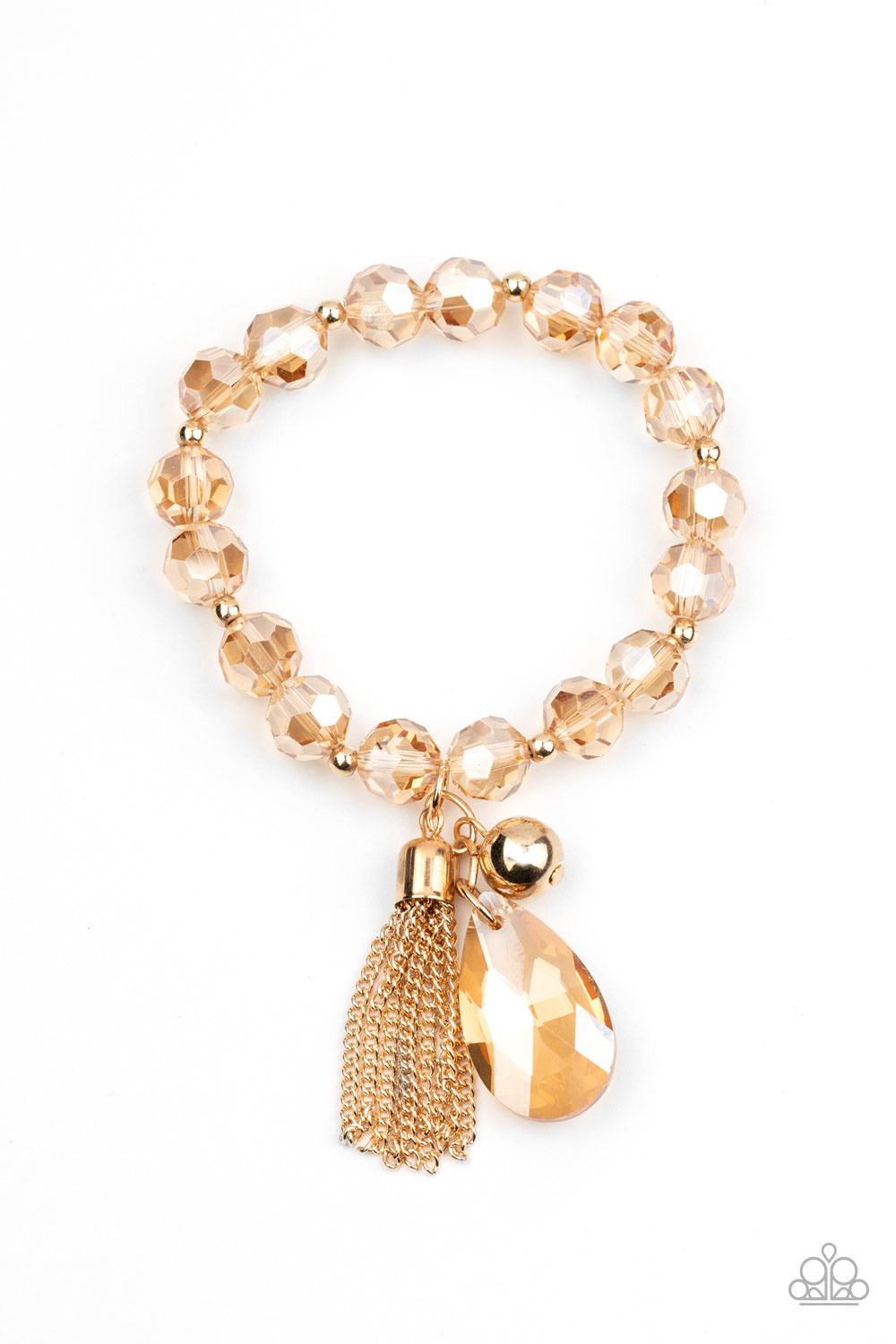 Paparazzi Accessories Leaving So SWOON? - Gold A collection of dainty gold beads and golden faceted crystal-like beads are threaded along stretchy bands around the wrist. A classic gold bead, golden teardrop crystal, and gold chain tassel swing from a gli