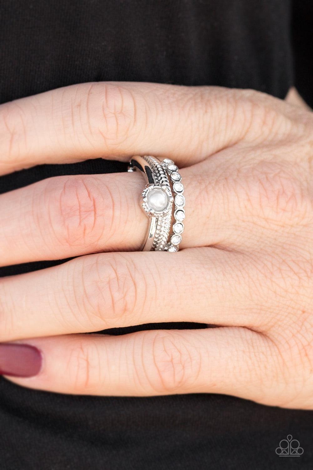Paparazzi Accessories STAR Raving Mad - White Featuring smooth, dotted, and rhinestone encrusted surfaces, glistening silver bands layer across the finger creating mismatched shimmer. A classic white pearl adorns the layers, creating a timeless centerpiec
