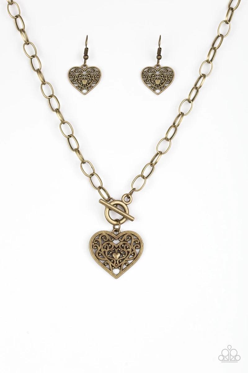 Paparazzi Accessories Victorian Romance ~Brass Brushed in an antiqued finish, brass filigree climbs a heart-shaped frame, creating a vintage inspired pendant below the collar. Features a toggle closure. Sold as one individual necklace. Includes one pair o