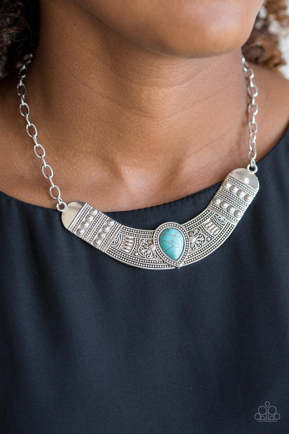 Paparazzi Accessories Very Venturous - Blue Embossed in floral and tribal inspired patterns, a shimmery silver crescent shaped frame swings below the collar in a fierce fashion. Chiseled into a tranquil teardrop, a refreshing turquoise stone is pressed in