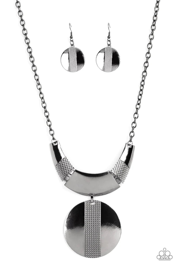 Paparazzi Accessories Metallic Enchantress - Black Three curved gunmetal bars, stamped in studded texture accents, connect to a gunmetal chain across the collar. An oversized gunmetal disc, divided down the center with texture, swings from the bottom resu