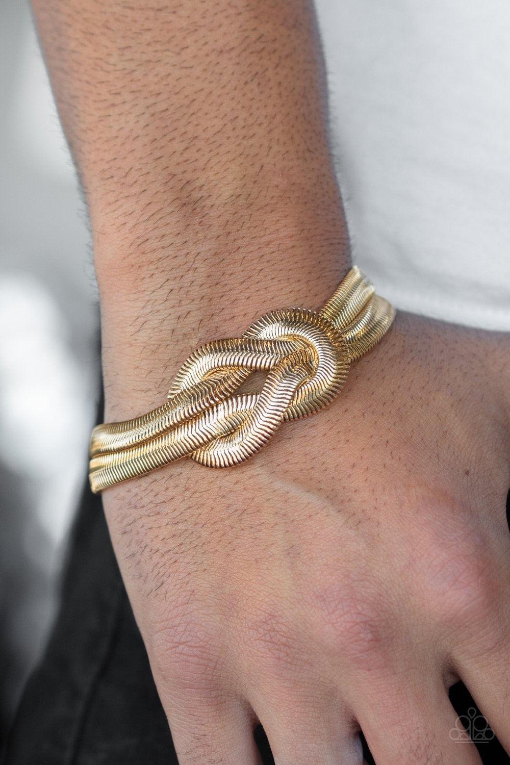 Paparazzi Accessories To The Max ~Gold Two thick rows of gold herringbone chain knot into a bold centerpiece atop the wrist. Features an adjustable clasp closure.