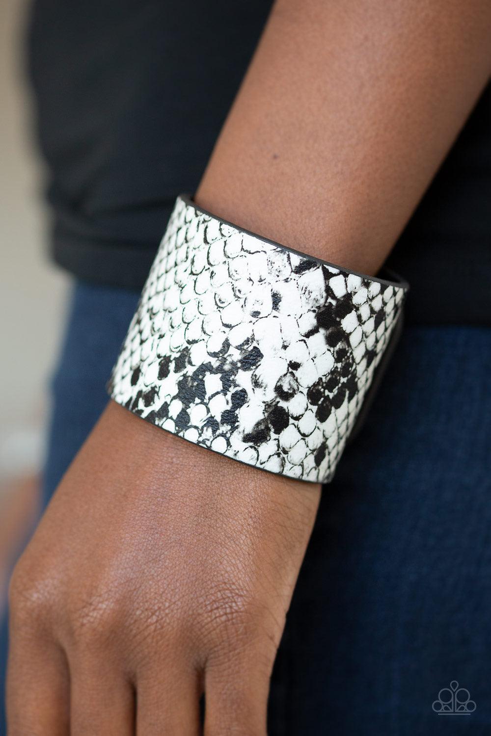 Paparazzi Accessories What’s HISS Is Mine ~White Featuring black and white python print, a thick black leather band wraps around the wrist for a wild look. Features an adjustable snap closure.