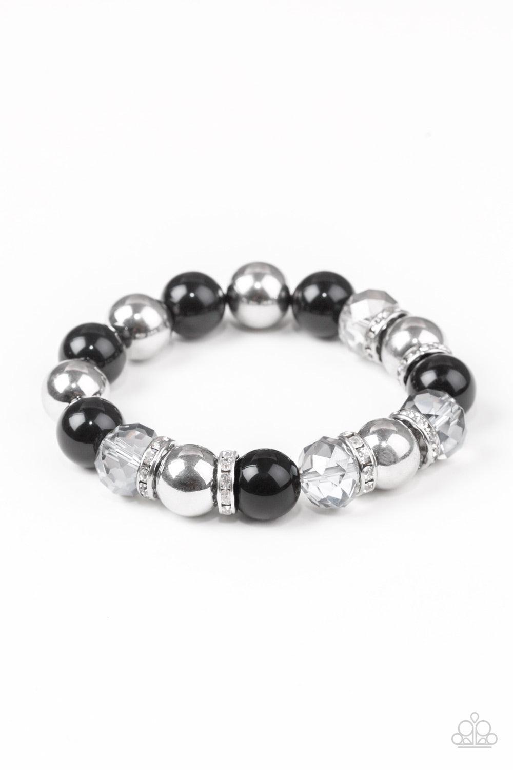 Paparazzi Accessories Camera Chic - Black Oversized silver, smoky crystal-like, and polished black beads are threaded along a stretchy elastic band and wrapped around the wrist for a glamorous look. White rhinestone encrusted rings are sprinkled between t