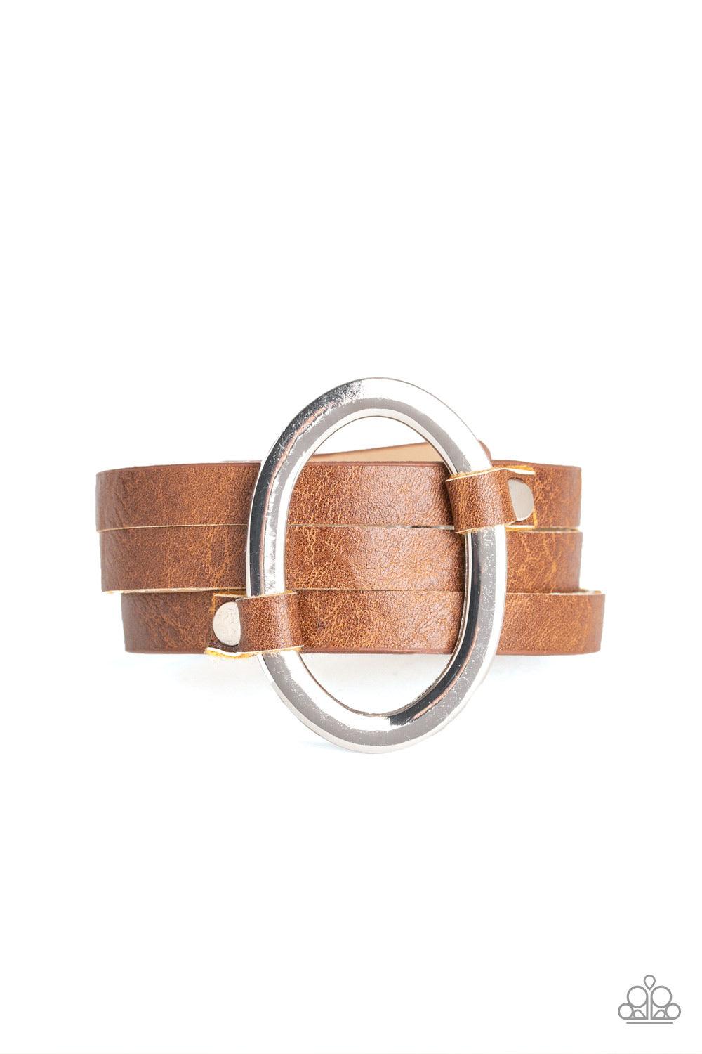 Paparazzi Accessories Cowgirl Cavalier - Brown An oval silver ring loops through two belt loop fittings and is studded in place across the front of a spliced brown leather band for a bold urban look. Features an adjustable snap closure. Jewelry