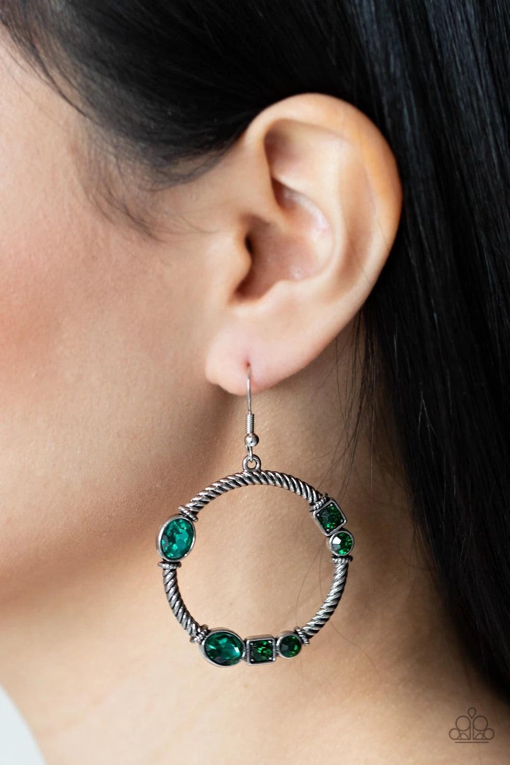 Paparazzi Accessories Glamorous Garland - Green Featuring round, oval, and square cuts, a collection of glittery green rhinestones haphazardly adorn the front of a textured silver hoop, for a gritty-glamorous look. Earring attaches to standard fishhook fi