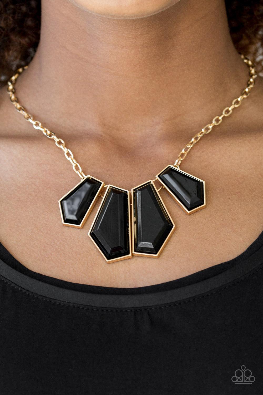 Paparazzi Accessories Get Up And Geo - Gold Featuring emerald-style cuts, faceted black beads are pressed into sleek gold frames. The colorful frames join at the bottom of a shimmery gold chain, creating a bold geometric fringe below the collar. Features