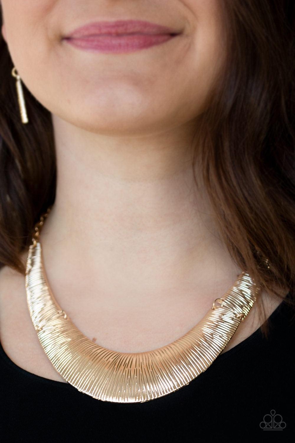 Paparazzi Accessories Feast Or Famine - Gold Etched in linear patterns, dramatic gold plates connect below the collar, joining into a fierce crescent-shaped pendant for a statement making look. Features an adjustable clasp closure. Jewelry