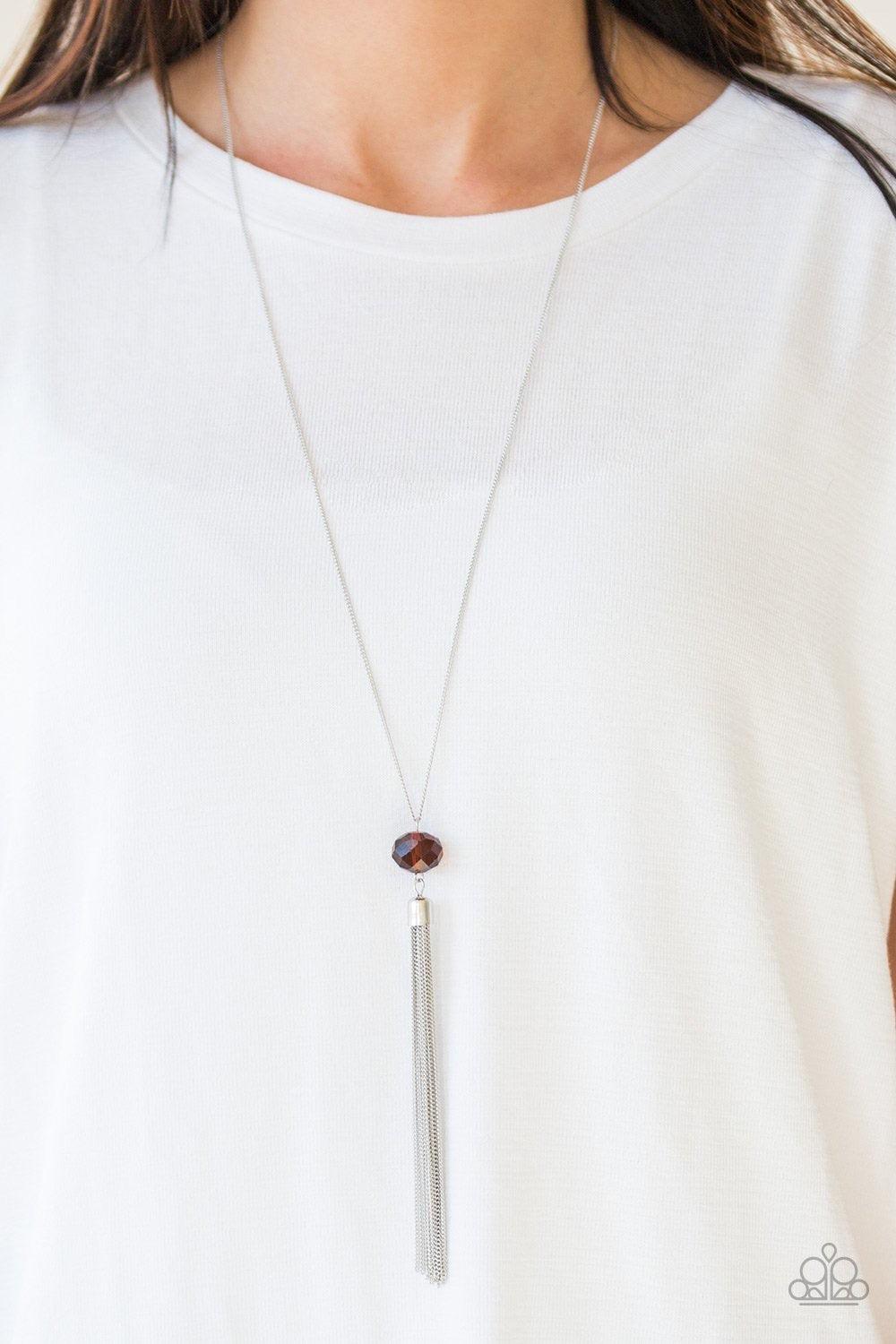 Paparazzi Accessories Socialite of the Season - Brown A glittery brown crystal-like bead swings from the bottom of a lengthened silver chain, giving way to a shimmering silver tassel for a glamorous finish. Features an adjustable clasp closure. Sold as on