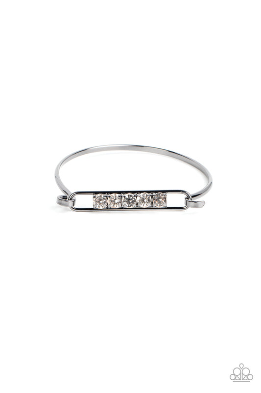 Paparazzi Accessories In CHARM’S Way - Black Encased in gunmetal square fittings, a row of glassy white rhinestones are fitted in place along an airy gunmetal frame that hinges to the center of a bangle-like bracelet for a timeless finish. Features a hing