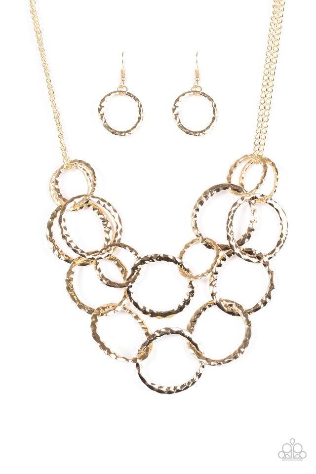 Paparazzi Accessories Radiant Ringmaster - Gold Varying in size, gold rings are delicately hammered with light catching shimmer. The glistening rings link below the collar, draping into two layered rows for an edgy finish. Features an adjustable clasp clo