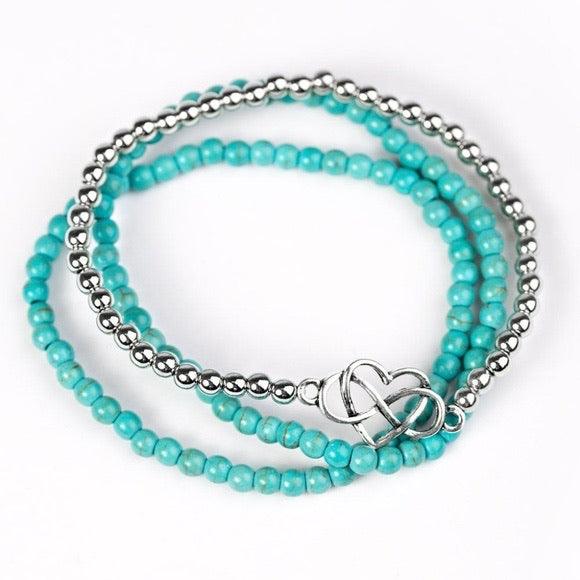 Paparazzi Accessories Collect Moments - Blue Vivacious blue/turquoise beads and classic silver beads are threaded along elastic stretchy bands, creating colorful layers across the wrist. Brushed in an antiqued shimmer, an airy heart charm adorns the cente