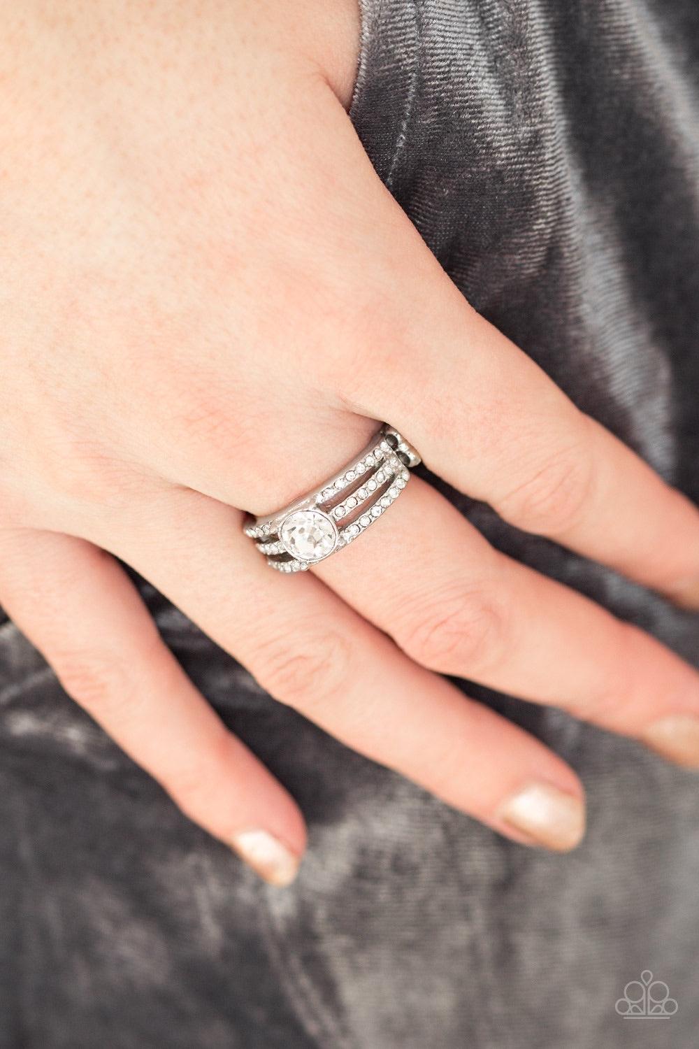 Paparazzi Accessories Champion Chic - White Encrusted in dainty white rhinestones, glistening silver bars layer across the finger, coalescing into a gorgeous band. A glittery white rhinestone is pressed into the center of the bands, creating a refined cen