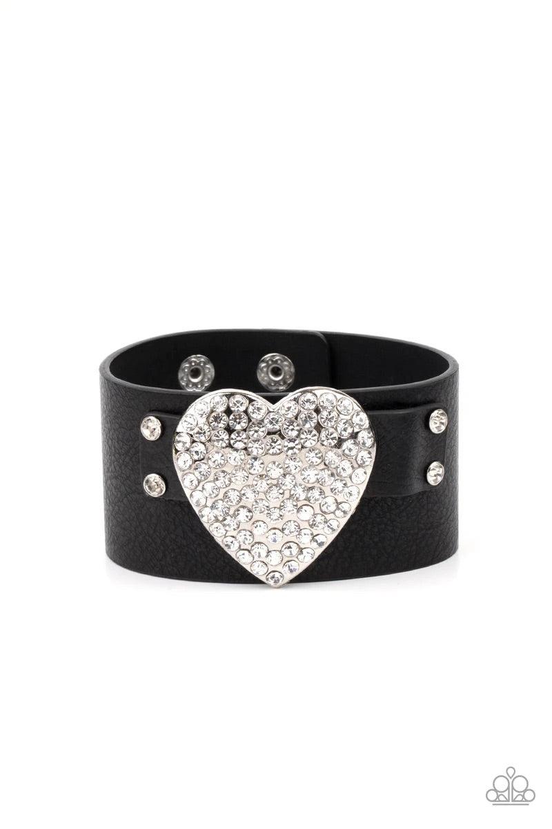 Paparazzi Accessories Flauntable Flirt - Black Encrusted in blinding white rhinestones, an oversized silver heart frame is studded in place across the front of a black leather band, creating a flirtatious centerpiece around the wrist. Features an adjustab