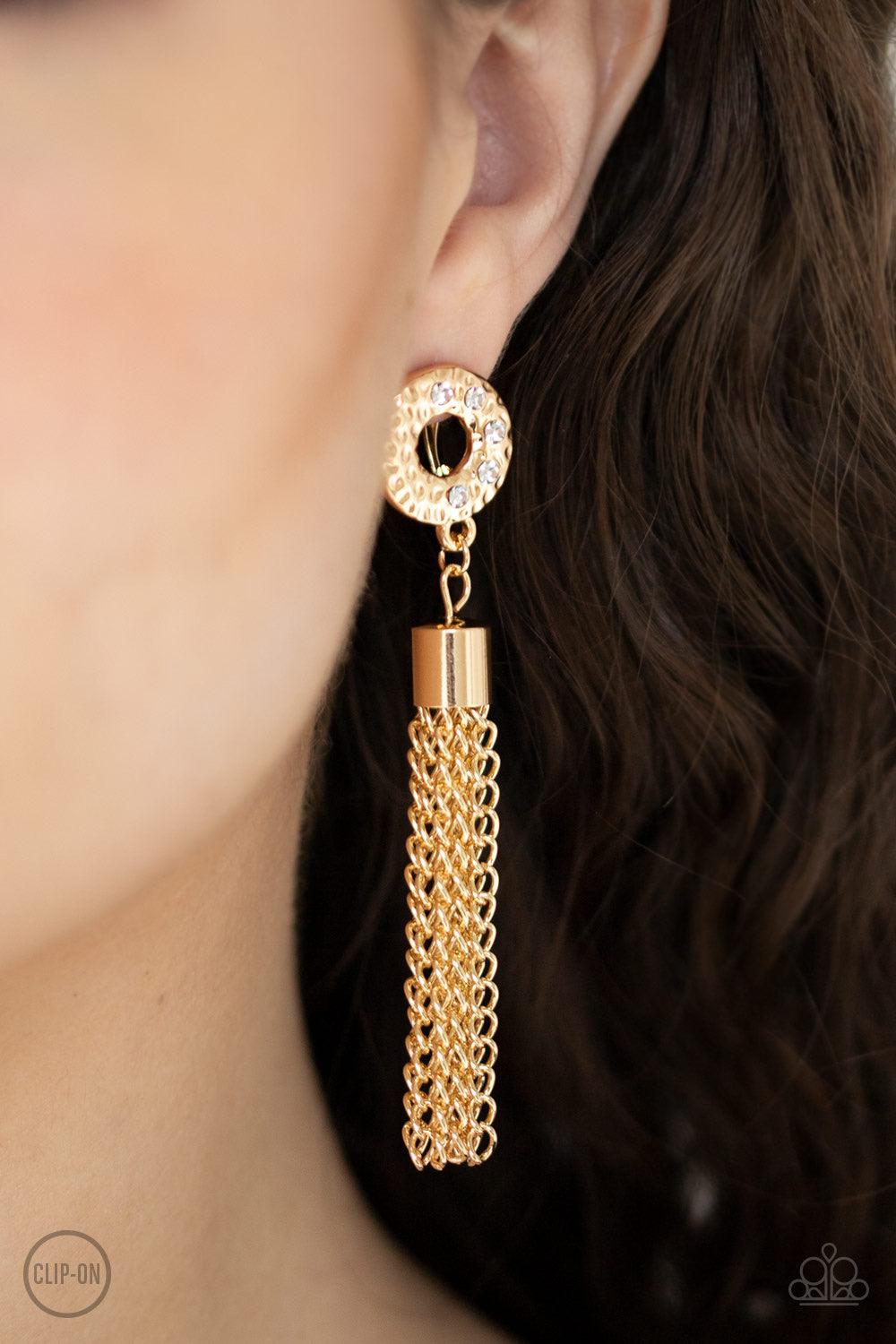 Paparazzi Accessories Perfectly Prestigious ~Gold *Clip-On A glistening gold tassel swings from the bottom of a hammered gold ring encrusted in sections of glassy white rhinestones for a refined look. Earring attaches to a standard clip-on fitting.